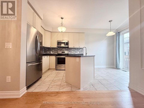 A kitchen with a refrigerator, microwave, oven and sink.