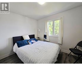 A bedroom with a bed, chair, and window.