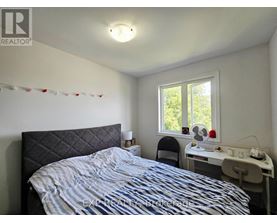 A bedroom with a bed, desk, chair, and window.