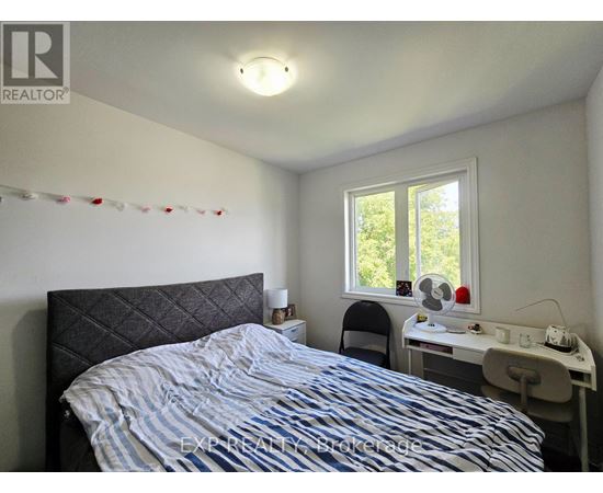 A bedroom with a bed, desk, chair, and window.