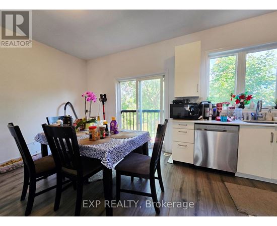 A dining room with a table set for four and a kitchen in the background.