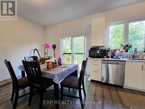 A dining room with a table set for four and a kitchen in the background.