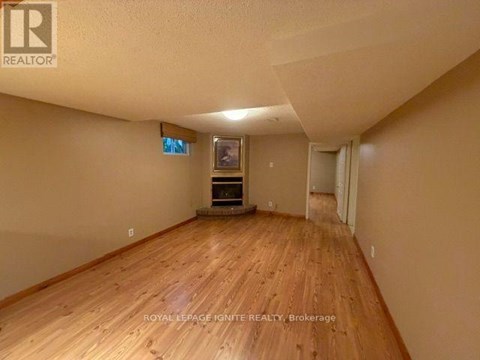 A room with wooden flooring and a flat screen TV mounted on the wall.