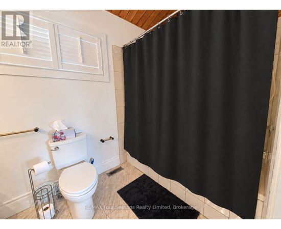 A white toilet with a black shower curtain in the background.