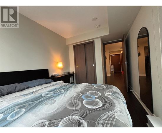 A bedroom with a large bed and a doorway leading to another room.