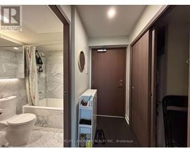 A bathroom with a toilet, a shower, and a small closet.