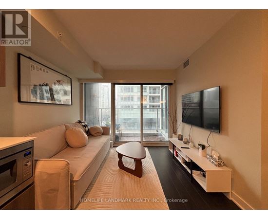 A living room with a white couch and a flat screen TV mounted on the wall.