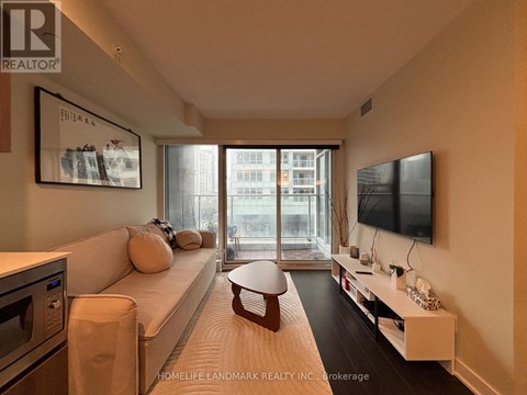 A living room with a white couch and a flat screen TV mounted on the wall.