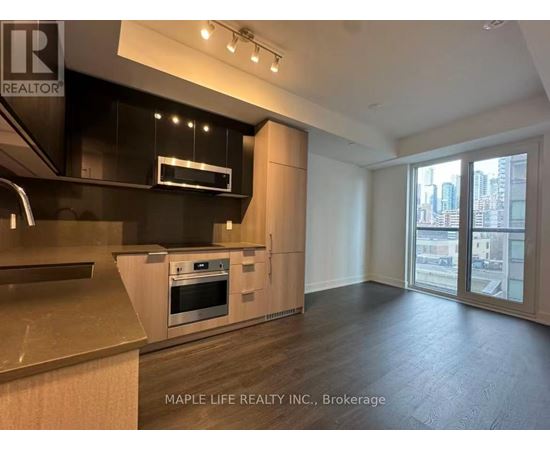 A modern kitchen with wooden floors and a large window.