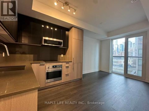A modern kitchen with wooden floors and a large window.