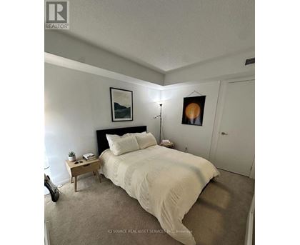 A bedroom with a bed, nightstand, and lamp.