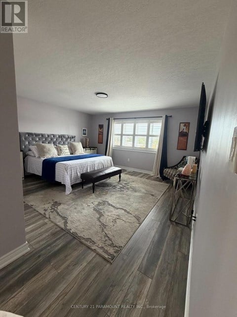 A bedroom with a bed, bench, and a rug.
