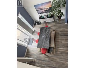 A living room with a grey wooden floor and a red chair.