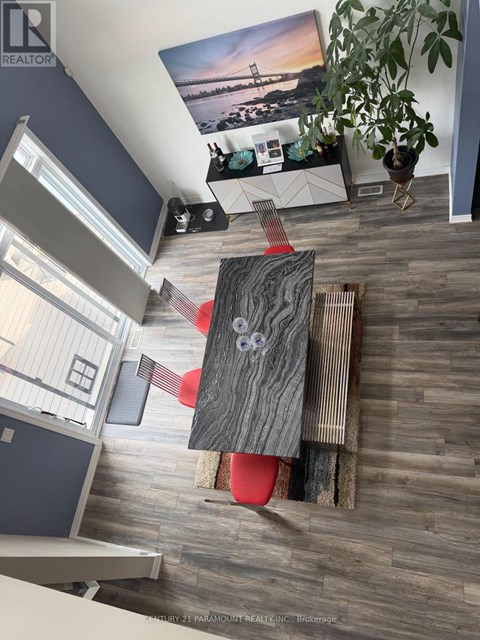 A living room with a grey wooden floor and a red chair.