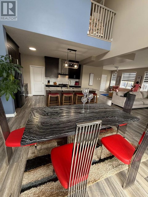 A modern dining room with a black table and red chairs.