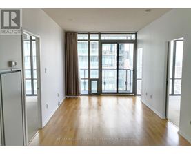A spacious room with wooden floors and large windows.