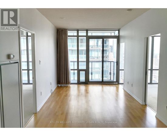 A spacious room with wooden floors and large windows.