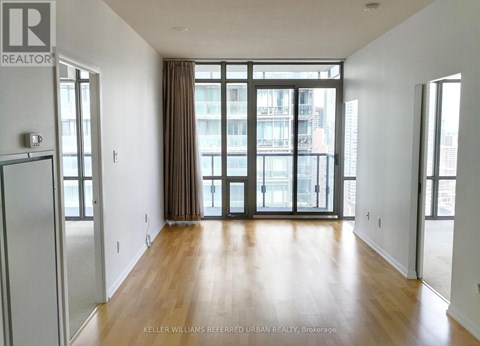 A spacious room with wooden floors and large windows.