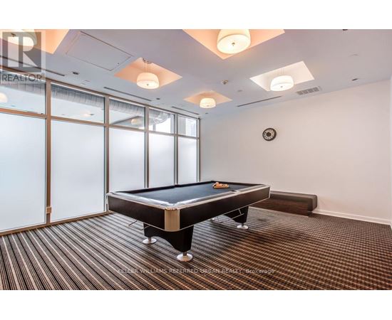 A pool table in a room with a clock on the wall.