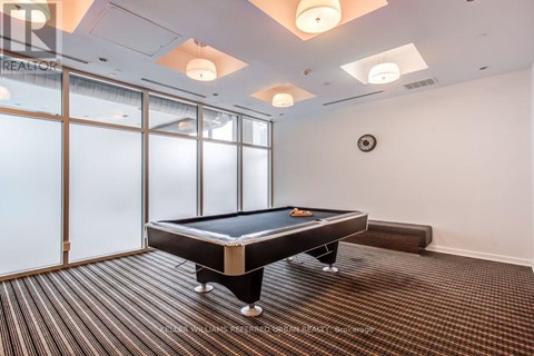 A pool table in a room with a clock on the wall.