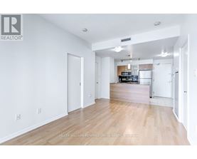 A spacious living room with hardwood floors and white walls.
