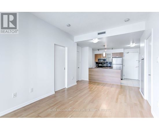 A spacious living room with hardwood floors and white walls.