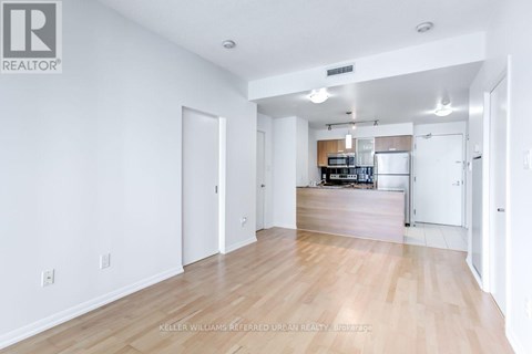 A spacious living room with hardwood floors and white walls.