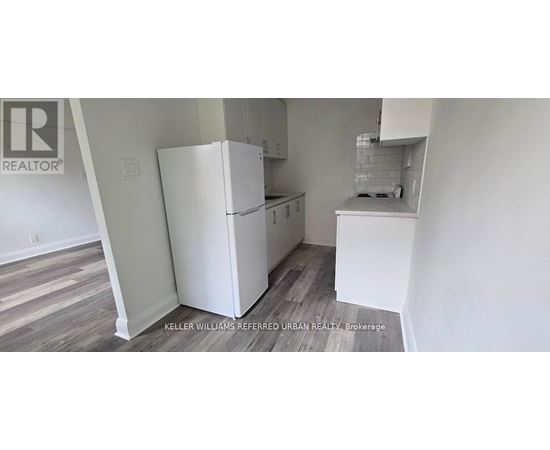 A white refrigerator in a kitchen with wooden floors.