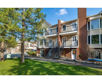 A multi-story apartment building with a balcony and stairs leading to the entrance.