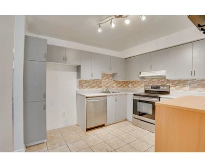 A kitchen with a refrigerator, oven, and cabinets.