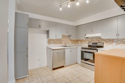 A kitchen with a refrigerator, oven, and cabinets.