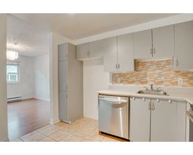 A kitchen with white cabinets and a brick backsplash.