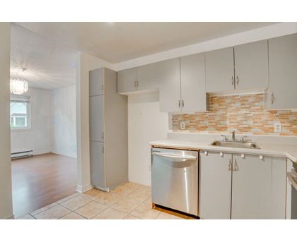 A kitchen with white cabinets and a brick backsplash.