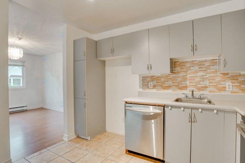 A kitchen with white cabinets and a brick backsplash.