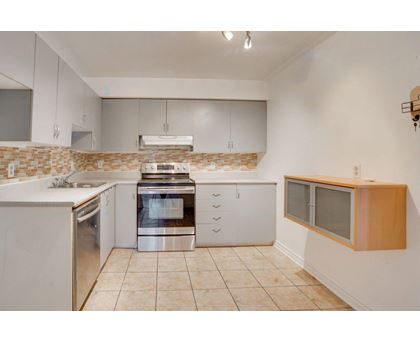 A kitchen with white cabinets and a tiled backsplash.