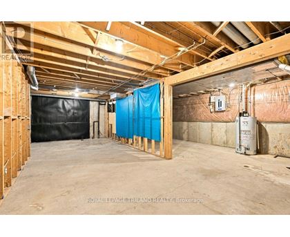 A spacious unfinished basement with a blue tarp covering a section of the wall.