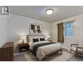 A bedroom with a bed, nightstands, and a chair.