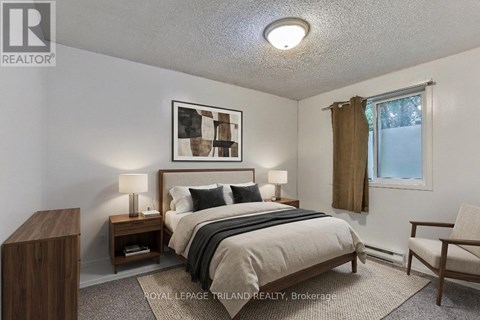 A bedroom with a bed, nightstands, and a chair.
