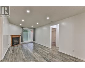 A spacious room with a fireplace and wood flooring.