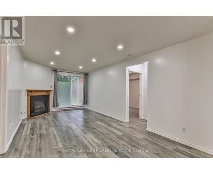 A spacious room with a fireplace and wood flooring.