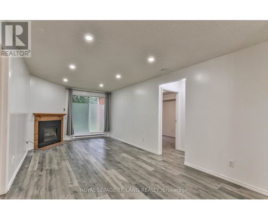 A spacious room with a fireplace and wood flooring.