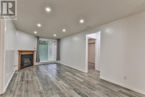 A spacious room with a fireplace and wood flooring.