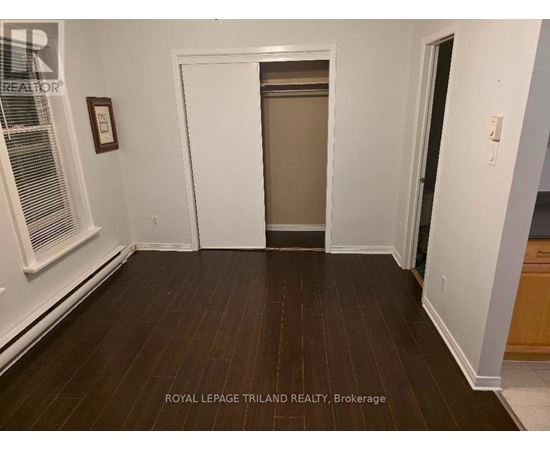 A room with wooden floors and white walls, with a door in the middle of the room.
