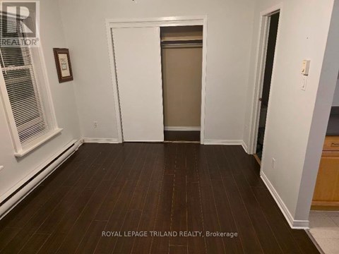 A room with wooden floors and white walls, with a door in the middle of the room.