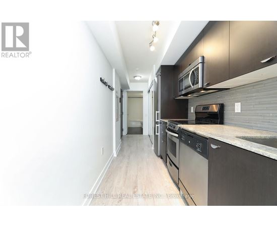 A modern kitchen with stainless steel appliances and wooden flooring.