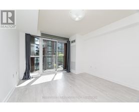 A spacious room with a sliding glass door leading to a balcony.