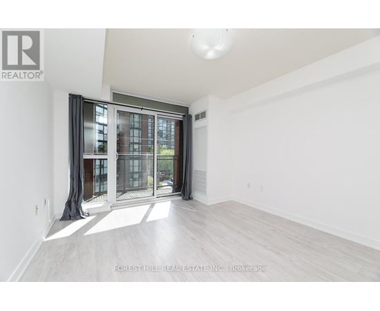 A spacious room with a sliding glass door leading to a balcony.