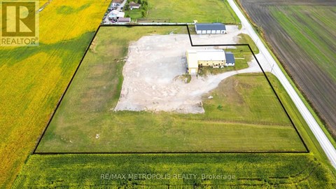 An aerial view of a property with a large open field and a building in the middle.