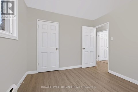 A room with two white doors and wooden flooring.