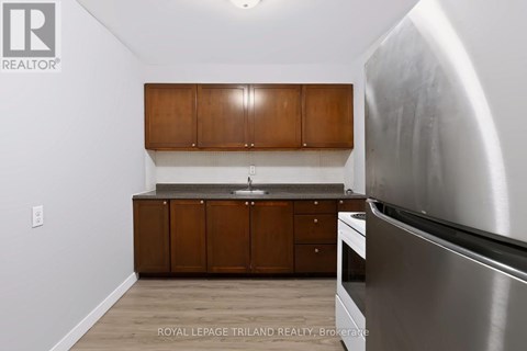A kitchen with wooden cabinets and a stainless steel refrigerator.